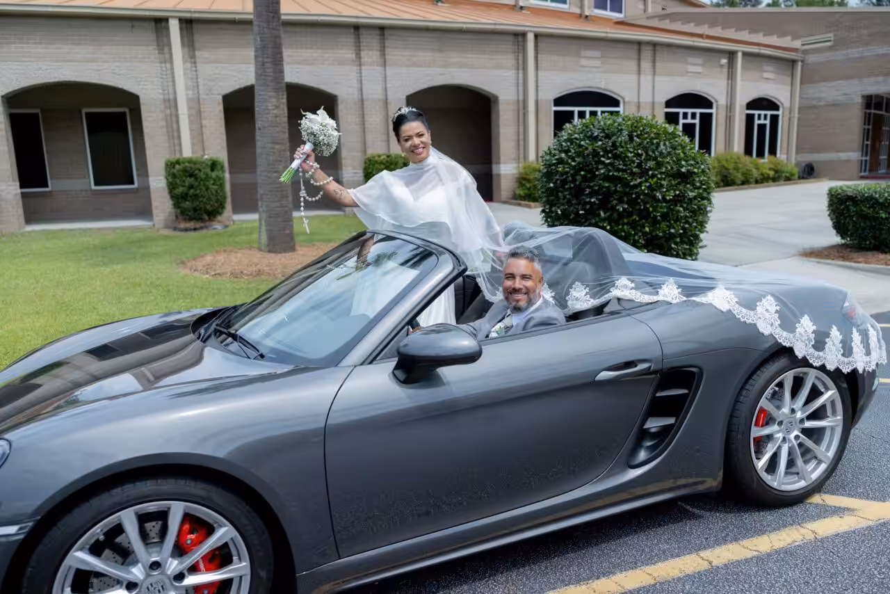 Bride waving her bouquet from a convertible while the groom drives, photographed by Studio FB USA