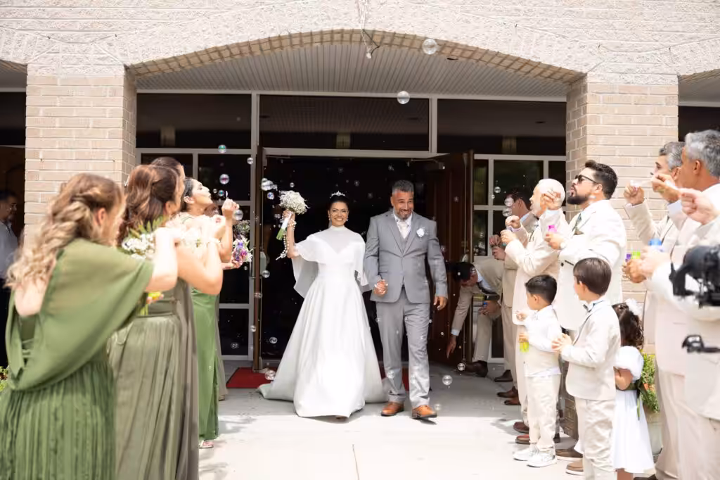 How to Choose a Wedding Photographer: 8 Mistakes to Avoid Bride and groom leaving a church through the main doors while guests on both sides cheer and toss petals